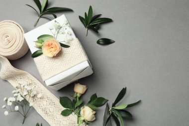 Çiçekçi. Kutu, çiçekler, yapraklar, ve gri arka planda kurdele, düz. Metin için boşluk