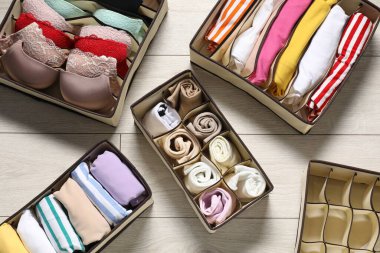 Ahşap zeminde katlanmış giysileri ve iç çamaşırları olan organizatörler.