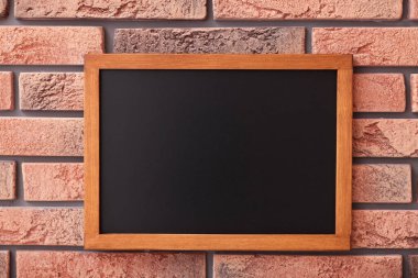 Tuğla duvarda boş küçük bir tahta.