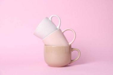 Pembe arkaplanda farklı fincanların yığını