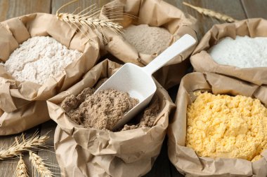 Tahta masadaki kağıt torbalarda farklı türde un, yakın plan.