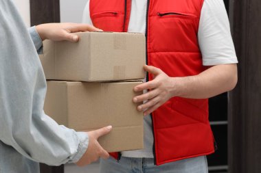 Kurye içerideki alıcıya paketler veriyor, yakın plan.