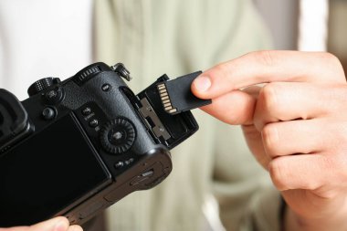 Bir adam fotoğraf makinesine SD bellek kartı yerleştiriyor.