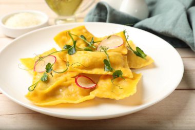 Mikroyeşillikli lezzetli ravioli ve ahşap masada turp, yakın plan.