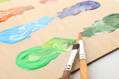 Beyaz arka planda boya ve fırçalı ahşap palet, yakın plan.