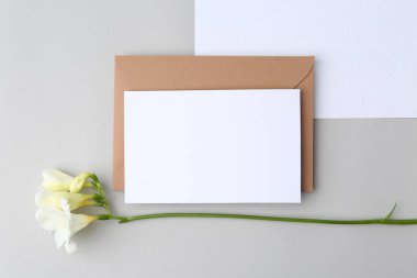 Boş tebrik kartı, kağıt zarf ve açık gri arka planda çiçek, düz uzanma