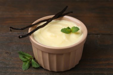 Lezzetli vanilyalı puding, nane ve kapsüller ahşap masada, yakın plan.
