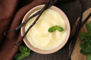 Tasty vanilla pudding, mint and pods on wooden table, flat lay