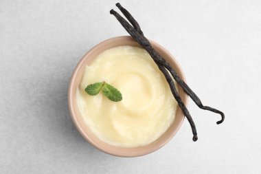 Lezzetli vanilyalı puding, nane ve kapsüller açık gri masada.