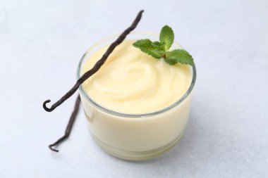 Lezzetli vanilyalı puding, nane ve kapsüller açık gri masada, yakın plan.