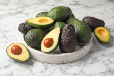 Avokadoların tamamı beyaz mermer masada, yakın plan.