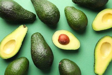 Avokadoların tamamı ve kesimi yeşil arka planda, düz.