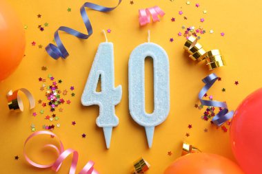 40. yaş günü. Turuncu arka planda numara şekilli mumlar ve parti dekoru, düz uzanma
