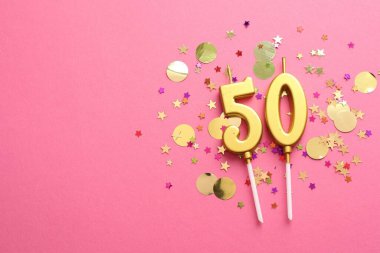50. yaş günü. Pembe arka planda mumlar ve konfetiler var. Metin için boşluk