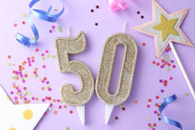50th birthday. Number shaped candles, confetti and party decor on violet background, flat lay
