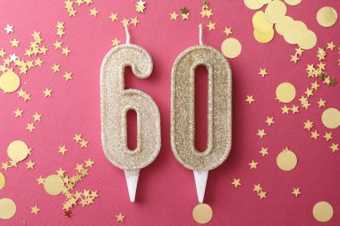 60th birthday. Number shaped candles and confetti on pink background, flat lay