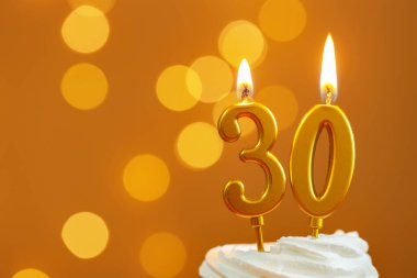 30. yaş günü. Kek üzerindeki mumların yanma sayısı altın arka planda bulanık ışıklar, yakın çekim ve metin için boşluk. Bokeh etkisi