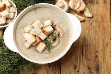 Lezzetli mantar kremalı çorba, kızarmış ekmek, dereotu ve malzemeler ahşap masada, düz yerde.