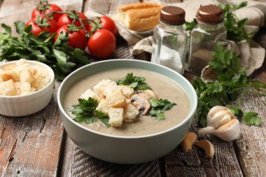 Lezzetli mantar kremalı çorba ve ahşap masada malzemeler, yakın plan.