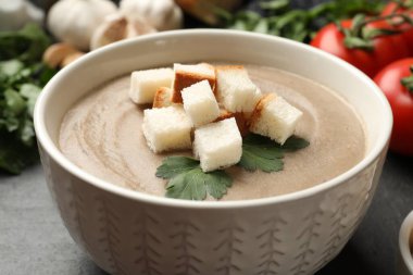 Ekmek arası mantar kremalı çorba ve siyah masada maydanoz, yakın plan.