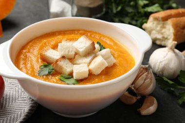 Kıtır ekmekli balkabağı kremalı çorba, maydanoz ve sarımsak karanlık masada, yakın plan.