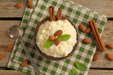 Tahta masada servis edilen bademli, nane ve tarçınlı lezzetli sütlaç.