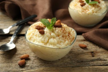 Tarçınlı lezzetli sütlaç, badem ve nane, ahşap masada servis edilir, yakın plan.