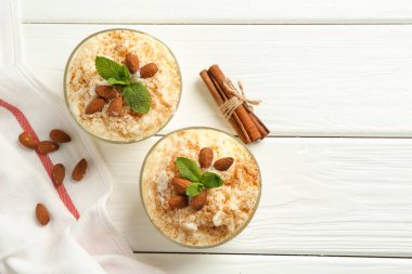 Tarçınlı sütlaç, badem ve nane şekerli beyaz ahşap masa, düz yatak. Metin için boşluk