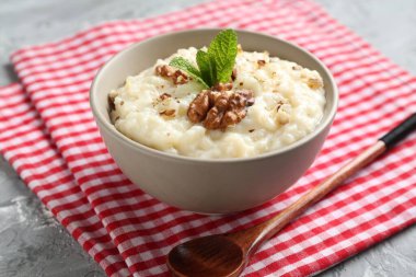 Cevizli lezzetli sütlaç, nane ve kaşık gri masada, yakın plan.