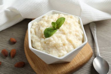 Bademli lezzetli sütlaç, nane ve kaşık ahşap masada, yakın plan.