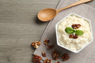 Cevizli leziz sütlaç, tahta masada nane ve kaşık, düz yatak. Metin için boşluk
