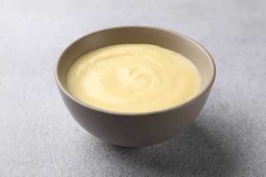 Açık gri masada kasede vanilyalı puding, yakın plan.