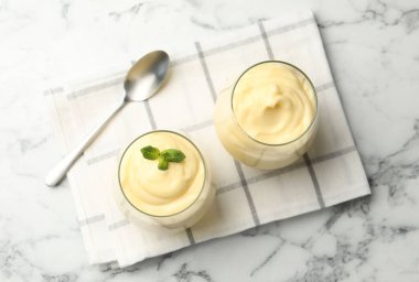 Beyaz mermer masada servis edilen nane aromalı vanilyalı puding.