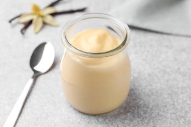 Lezzetli vanilyalı puding, kapsüller ve çiçek gri masada, yakın plan.