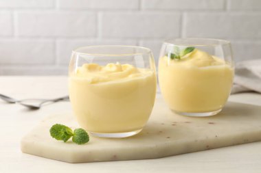 Beyaz ahşap masada naneli vanilyalı puding.