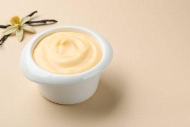 Kapsüllü vanilyalı puding ve bej arka planda çiçek, yakın plan. Metin için boşluk