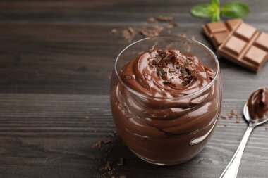 Bardakta çikolatalı puding ve tahta masada kaşık, yakın plan. Metin için boşluk