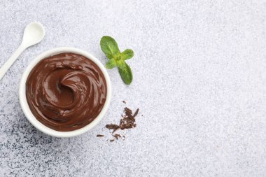 Kasede lezzetli çikolatalı puding, talaş, nane ve kaşık açık gri desenli masa, düz yatak. Metin için boşluk
