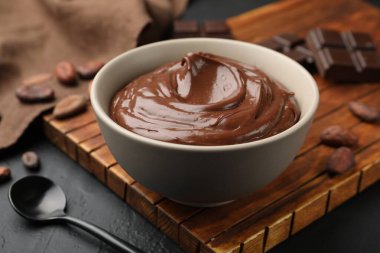 Kasede lezzetli puding, çikolata parçaları ve siyah masada kakao çekirdeği, yakın plan.