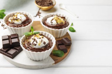 Krem şantili lezzetli puding ve beyaz ahşap masa üzerinde çikolata parçaları, metin için yer