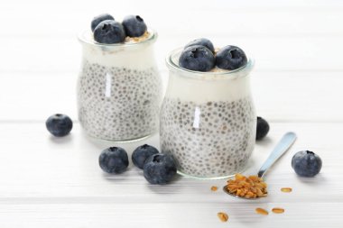 Chia tohumlu lezzetli puding, yoğurt, yaban mersini ve tahıl gevreği beyaz ahşap masada, yakın plan. Süper yemek.