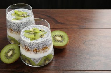 Süper yemek. Chia tohumlu lezzetli tatlı, yoğurt, tahıl gevreği ve ahşap masada kivi, yakın plan. Metin için boşluk