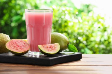 Guava suyunu tazeliyorum ve ahşap masada taze meyveler, yakın plan. Metin için boşluk