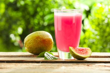 Guava suyunu tazeliyorum ve ahşap masada taze meyveler, yakın plan.