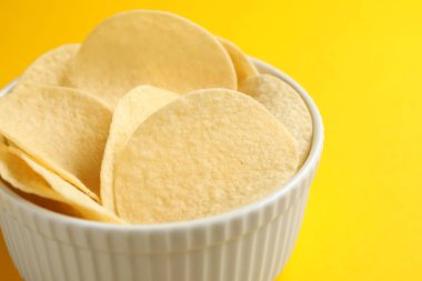 Sarı arka planda lezzetli patates cipsi, yakın plan.