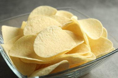 Gri masada lezzetli patates cipsleri, yakın plan.