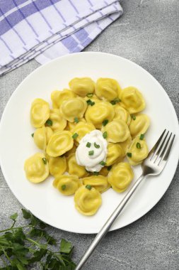 Taze soğanlı lezzetli börekler, ekşi krema ve çatal gri desenli masa, düz uzanmış