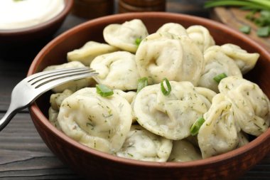 Taze soğanlı lezzetli hamur tatlısı, ahşap masada dereotu ve çatal, yakın plan.