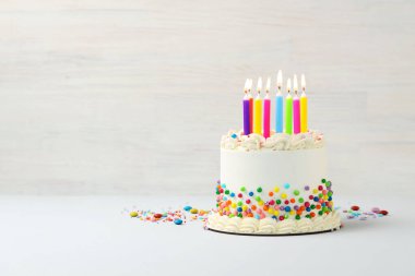 Renkli süslemeli nefis bento keki ve beyaz masada yanan mumlar. Metin için boşluk