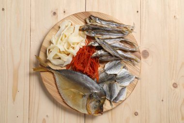 Ahşap masada birçok farklı kurutulmuş balık aperatifleri, üst manzara.